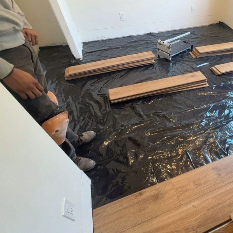 New luxury vinyl plank flooring being installed over a fresh moisture barrier